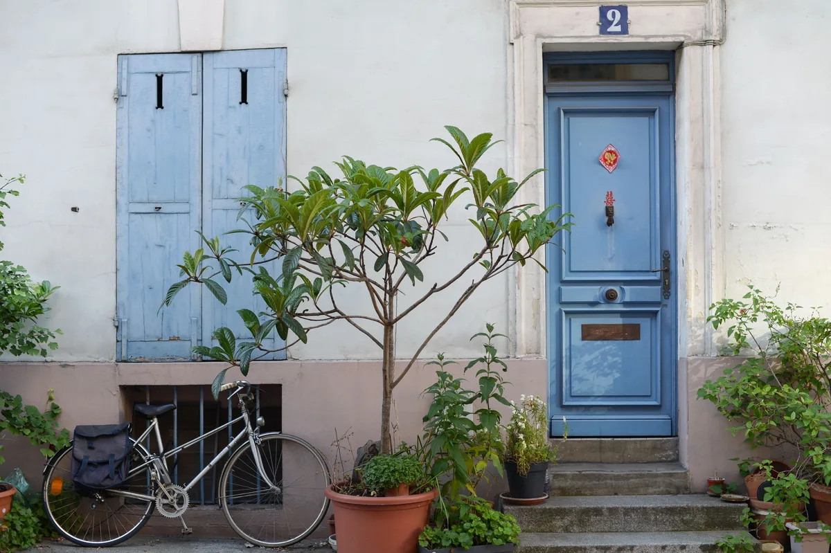 Porte d'entrée bleue d'une maison de ville, avec heurtoir, boîte aux lettres et volets